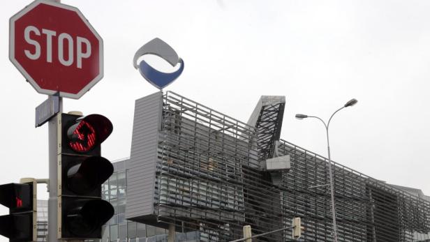 Ein Stoppschild und eine rote Ampel vor einem modernen Bürogebäude.