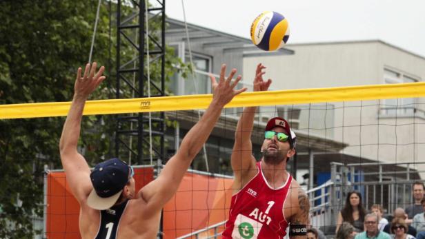 Zwei Beachvolleyballspieler kämpfen um den Ball über dem Netz.