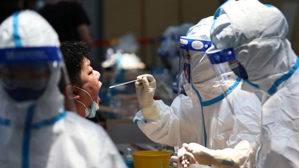 Medical worker collects a swab for nucleic acid testing at a sports centre in Nanjing