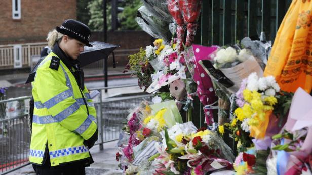 epa03715084 A British police woman reads messages of condolence left by members of the public at the scene where Drummer Lee Rigby, 2nd Battalion The Royal Regiment of Fusiliers was murdered in John Wilson street, Woolwich, South London, England 24 May 2013. A major police operation was launched on 22 May 2013 after two suspected terrorists murdered Lee Rigby in John Wilson Street, Woolwich, south-east London, England, 22 May 2013. EPA/FACUNDO ARRIZABALAGA