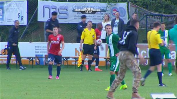 Ein Fußballspiel mit Spielern in roten, grünen und gelben Trikots auf dem Feld.