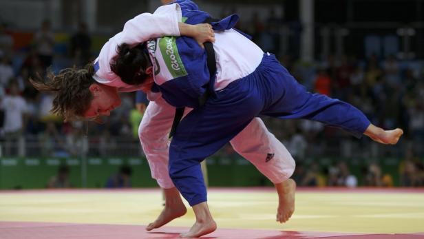 Zwei Judoka kämpfen auf einer roten Matte.