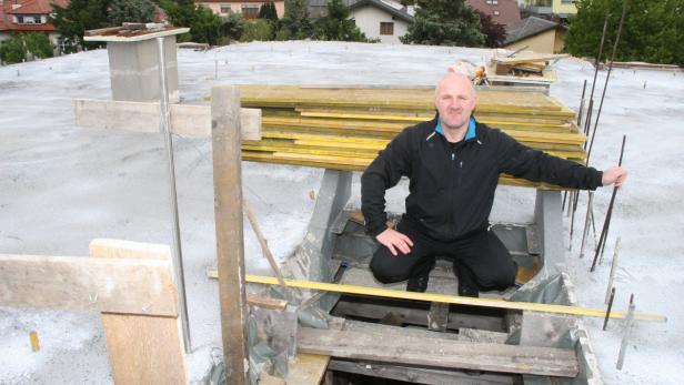 Ein Mann hockt auf einer Baustelle auf einem Dachboden.