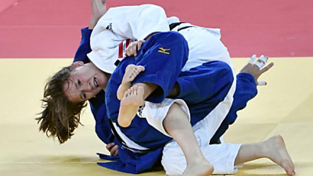 Zwei Judoka kämpfen auf der Matte, eine in einem blauen Anzug, die andere in Weiß.
