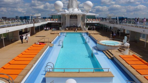 Ein Schwimmbad und Liegestühle auf dem Deck eines Kreuzfahrtschiffes.