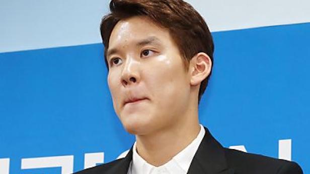 Ein Mann in einem schwarzen Anzug blickt zur Seite.