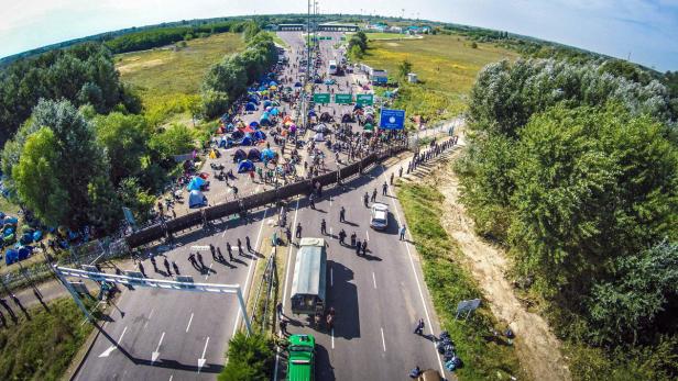 Luftaufnahme eines Grenzübergangs mit vielen Menschen und Zelten.
