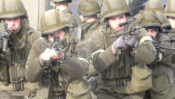 Eine Gruppe Soldaten in olivgrüner Uniform zielt mit ihren Gewehren.