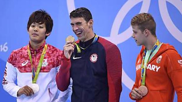Michael Phelps und andere Schwimmer bei einer Siegerehrung mit olympischen Medaillen.