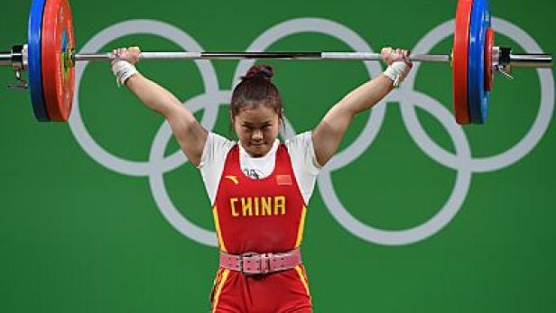 Eine chinesische Gewichtheberin stemmt eine Hantel über ihrem Kopf.