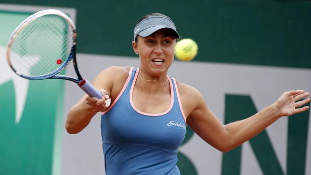 Eine Tennisspielerin schlägt einen Ball mit ihrem Schläger.