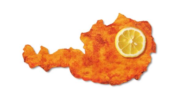Ein Wiener Schnitzel in der Form von Österreich mit einer Zitronenscheibe darauf.