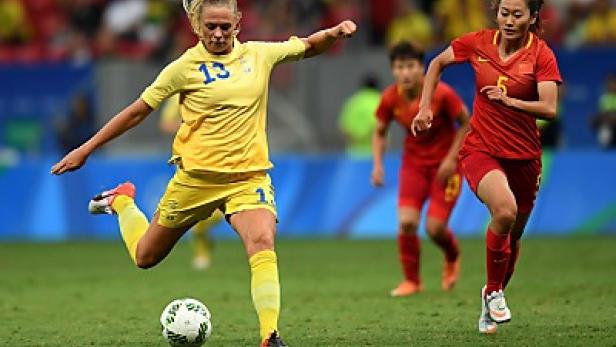 Eine schwedische Fußballspielerin schießt den Ball, während eine chinesische Spielerin zusieht.