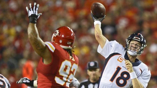 Ein Footballspieler der Denver Broncos wirft den Ball, während ein Spieler der Kansas City Chiefs ihn blocken will.