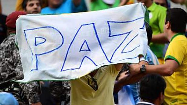 Eine Person hält ein Banner mit der Aufschrift „PAZ“ (Frieden).