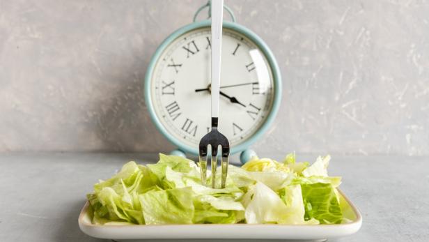 Ein Teller mit Salat vor einer Uhr.