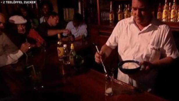 Ein Barkeeper bereitet an einer Bar einen Cocktail zu.