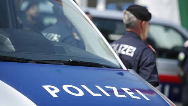 Eine Polizistin steht neben einem Polizeiauto.