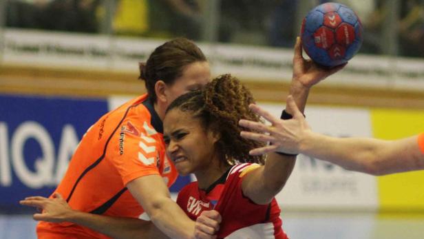 Eine Handballspielerin wirft den Ball, während sie von einer Gegenspielerin bedrängt wird.