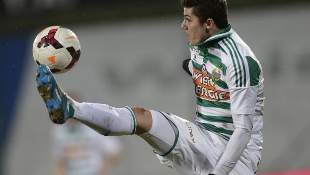Ein Fußballspieler in weiß-grünem Trikot schießt einen Ball.