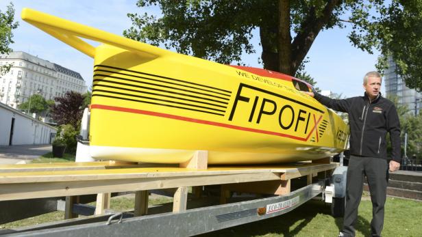 Ein Mann steht neben einem gelben Rennboot mit der Aufschrift „FIP OFIX“ auf einem Anhänger.