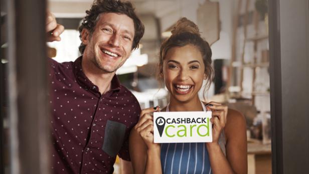 Ein Mann und eine Frau lächeln und halten ein Schild mit der Aufschrift „Cashback Card“.
