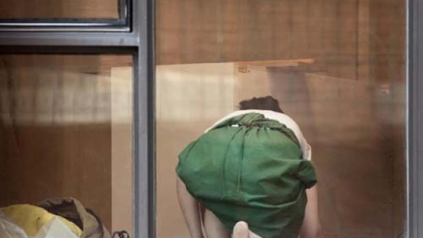 Eine Person kniet vor einem Fenster und scheint etwas zu putzen.