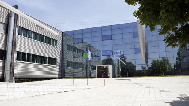 Das moderne Gebäude der HTBLVA Ferlach mit Glasfassade und Skulptur im Außenbereich.
