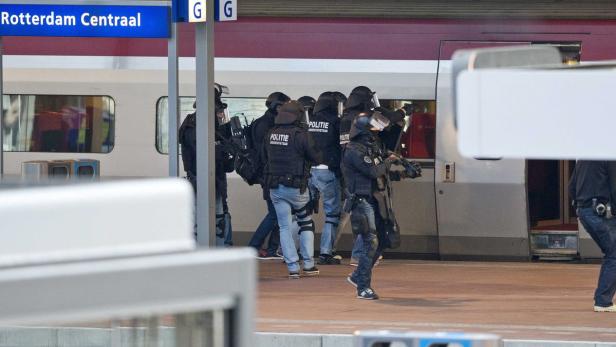 Polizisten mit Schutzhelmen und Waffen stehen am Bahnhof Rotterdam Centraal vor einem Zug.