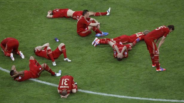 Mehrere erschöpfte Fußballspieler liegen auf dem Rasen.