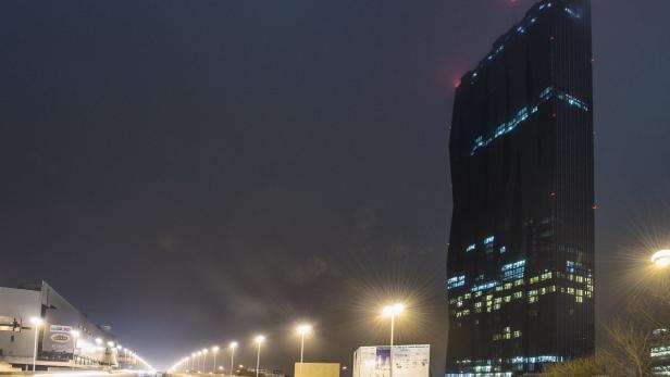 Nachts erstrahlt der DC Tower in Wien neben einer beleuchteten Straße.
