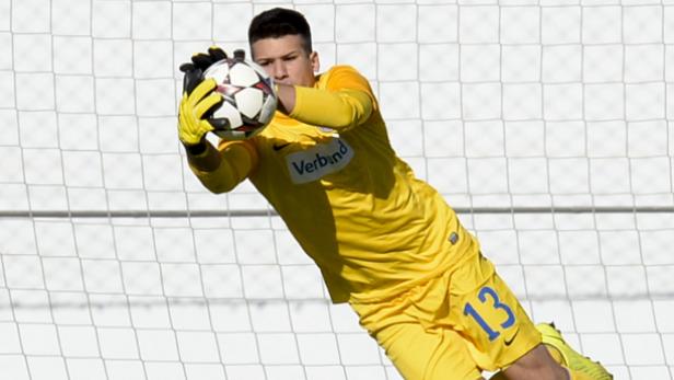 Ein junger Torwart fängt einen Fußball in der Luft.