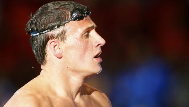 Ein nasser Schwimmer mit Schwimmbrille blickt zur Seite.