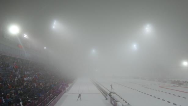 Ein Skilangläufer auf einer verschneiten Strecke bei nebligen Bedingungen.