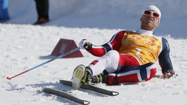 Ein erschöpfter Skilangläufer liegt im Schnee.