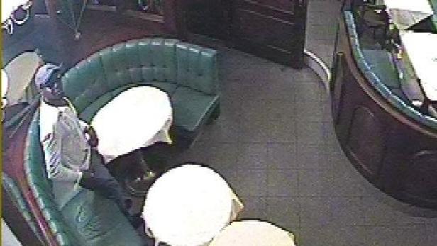 Ein Mann mit Hut sitzt in einem Restaurant und raucht eine Pfeife.