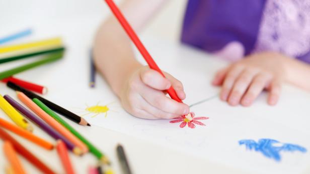Cute girl drawing a picture with colorful pencils