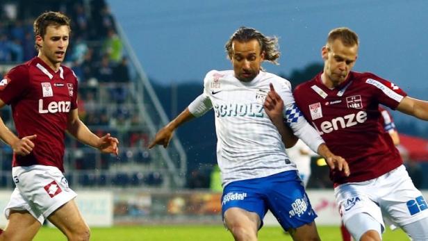 Drei Fußballspieler während eines Spiels auf dem Rasen.