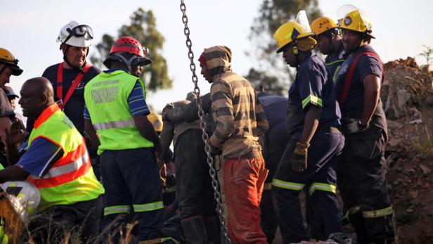 Eine Gruppe von Rettungskräften und Minenarbeitern steht beieinander.
