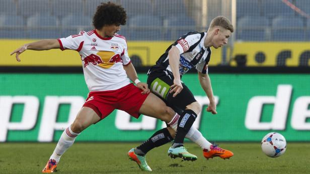 Zwei Fußballspieler kämpfen um den Ball auf dem Spielfeld.