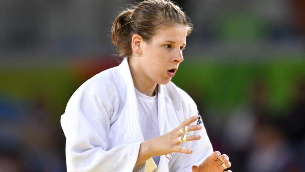 Eine Judoka im weißen Gi mit bandagierten Fingern.