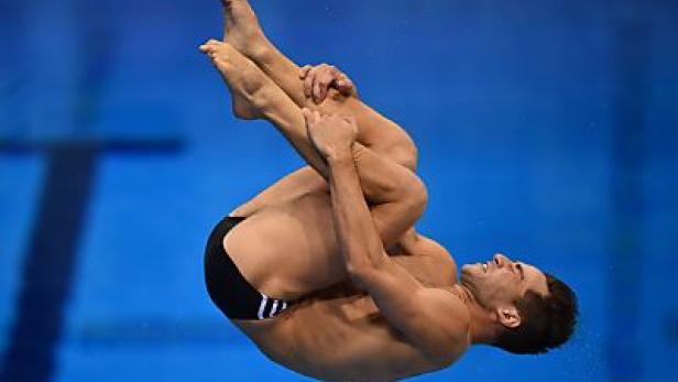 Ein männlicher Turmspringer während eines Sprungs in ein Schwimmbecken.
