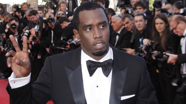 P. Diddy im Smoking posiert vor einer Wand von Fotografen.