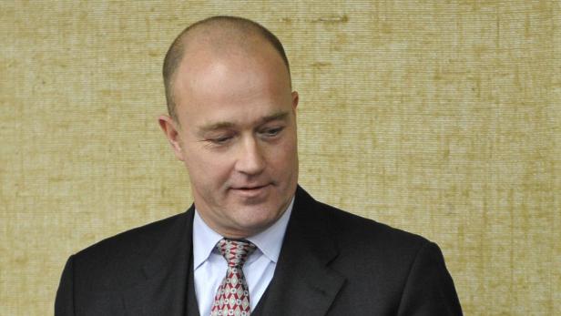 Ein Mann mit Anzug und Krawatte blickt nach unten.