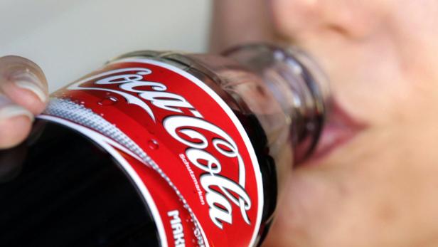 Eine Person trinkt aus einer Glasflasche Coca-Cola.