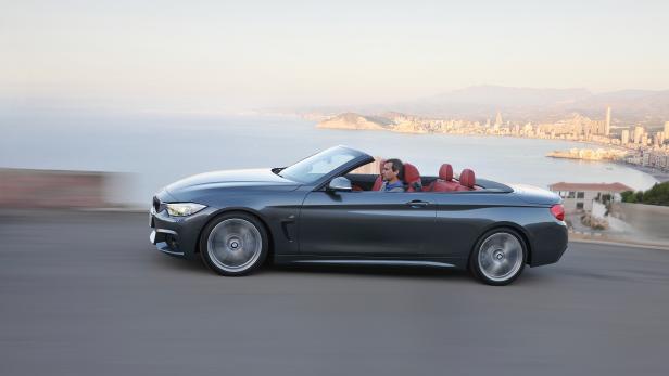 Ein graues BMW Cabriolet fährt auf einer Küstenstraße entlang.