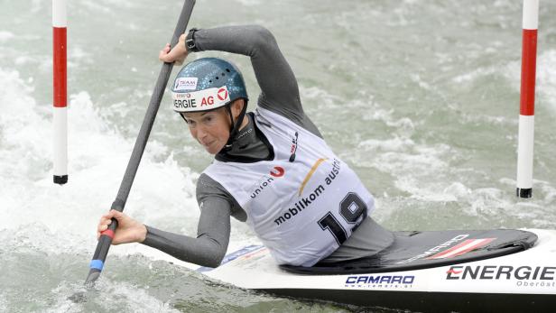Eine Frau paddelt in einem Kajak durch Wildwasser.