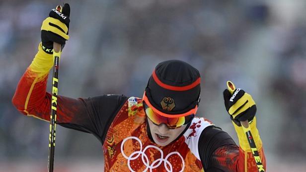 Ein deutscher Skilangläufer bei einem Wettkampf, erkennbar an der Kleidung mit den olympischen Ringen und der Deutschlandflagge.