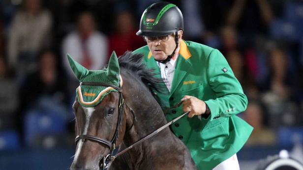 Ein Reiter in grüner Jacke und Helm auf einem Pferd.