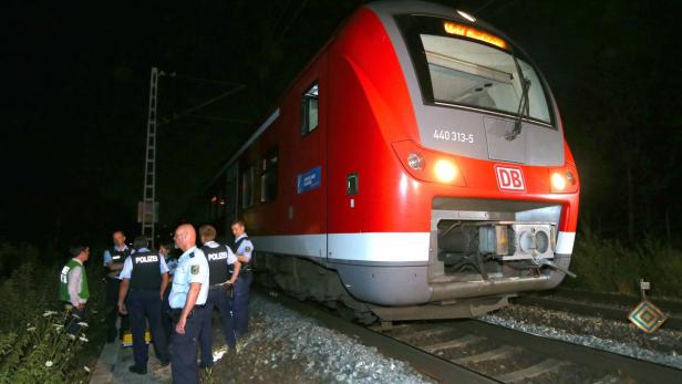 Ein roter Zug der Deutschen Bahn steht nachts auf den Gleisen, umringt von Polizisten.